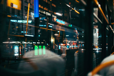 Illuminated city seen through window of bus at night