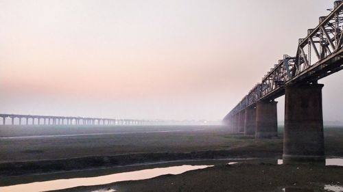 Bridge over sea against sky during sunset