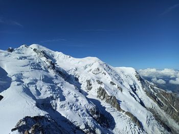 Scenic view of snowcapped mountains against blue sky