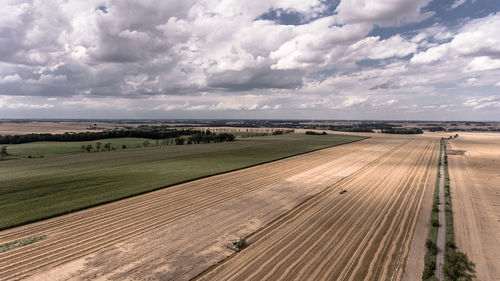 Scenic view of agricultural field against cloudy sky