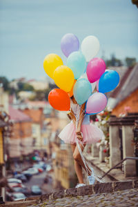 Full length of girl holding balloons against sky