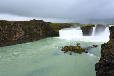 Scenic view of waterfall against sky