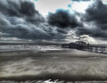 Scenic view of beach against cloudy sky