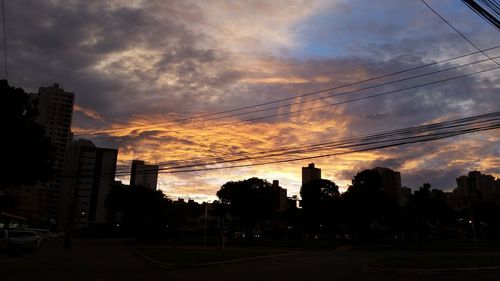 Silhouette of buildings against cloudy sky at sunset