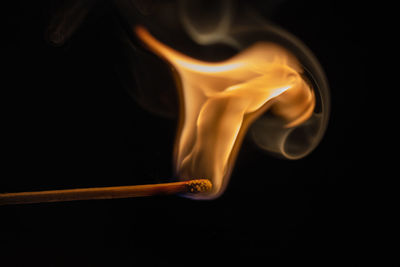 Close-up of burning match  against black background