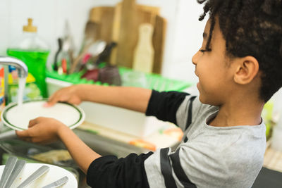 Close-up of boy washing dishes