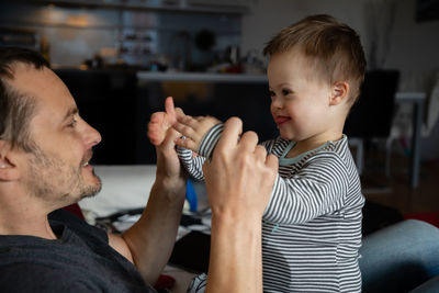 Happy mid adult man and son with down syndrome playing at home