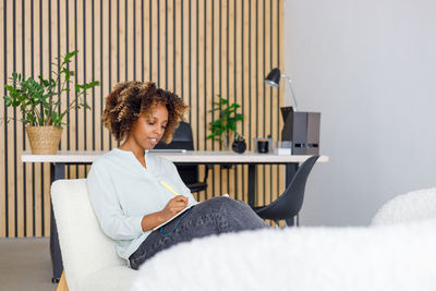 Young woman using laptop while sitting on bed at home