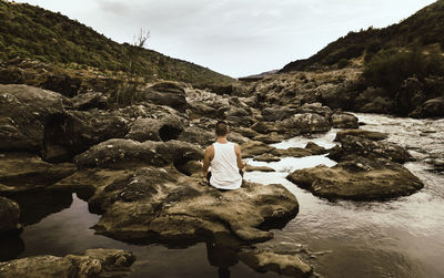 Rear view of woman sitting on rock