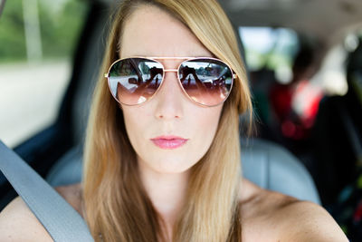 Portrait of woman wearing sunglasses while sitting in car