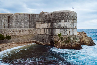 View of building by sea against cloudy sky