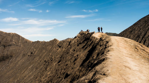 People standing on mountain against sky