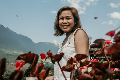 Portrait of smiling young woman on mountain against sky