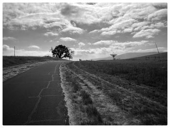 Road amidst field against sky