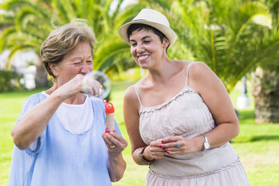 Happy mother and daughter playing with bubbles at park