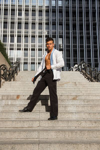 Portrait of man wearing fully unbuttoned shirt while standing on steps