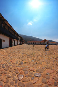 Cobbled footpath by buildings against sky