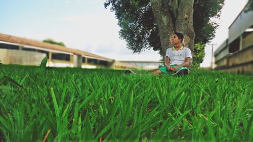Thoughtful young man sitting on grassy field
