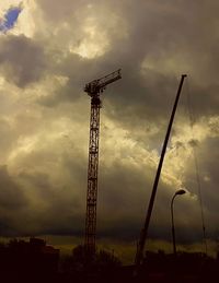 Low angle view of silhouette crane against dramatic sky