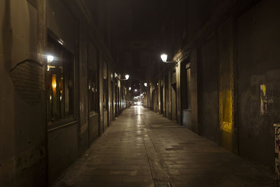 Empty narrow street along buildings at night