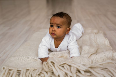 Portrait of cute baby sitting on bed at home