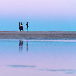 People walking on beach against sky