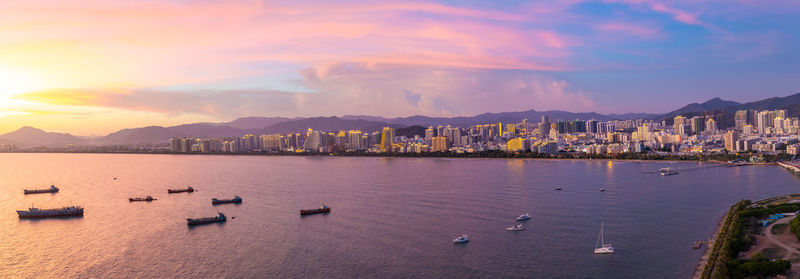 Scenic view of sea and cityscape against sky during sunset