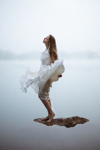 Portrait of young woman standing against sky