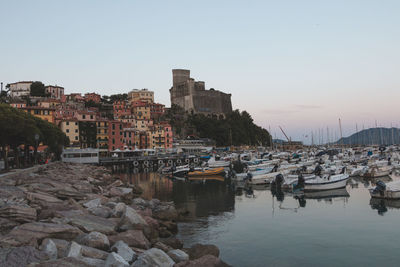 Boats moored in harbor against buildings in city