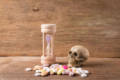 Close-up of hourglass with skull and medicines on wooden table
