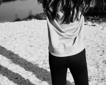 Rear view of woman standing on peeble beach