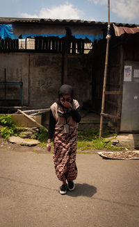A girl wearing batik is crossing the street