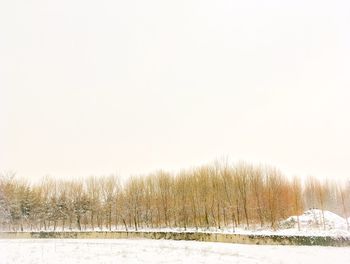 Snow covered field against clear sky