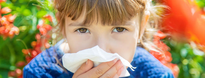 Portrait of sick girl having allergy wiping nose