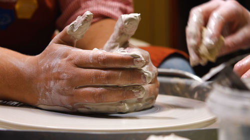 Close-up of a woman's hands stained with clay. work in a pottery workshop on a potter's wheel