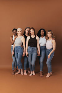 Studio shot of six women standing together holding their hands and looking at camera 