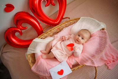 Valentine's day, a little girl in a basket against the background of hearts