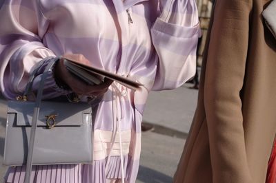 Midsection of woman holding purse on street