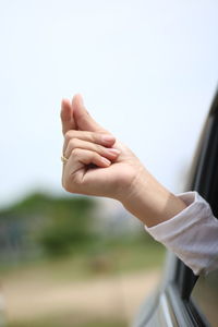 Cropped hand of woman snapping by car window