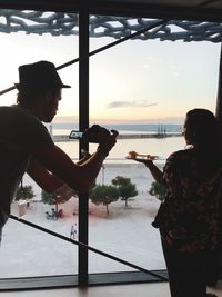 Side view of man standing by railing against sea