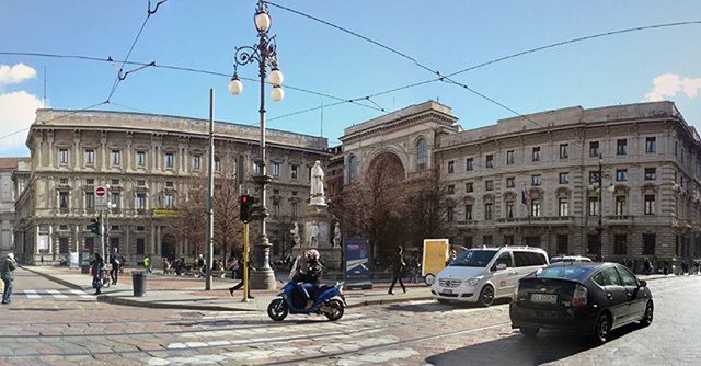 architecture, building exterior, built structure, street, transportation, city, car, land vehicle, people, clear sky, mode of transport, city life, road, travel, walking, sunlight, incidental people, day