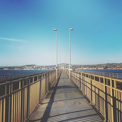 Bridge over sea against clear blue sky