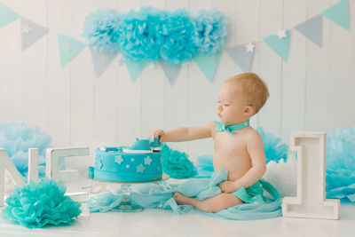 Birthday party for a one-year-old boy in blue and turquoise garlands and a cake, holiday concept 