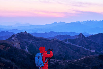 Man photographing great wall of china on mountain against sky