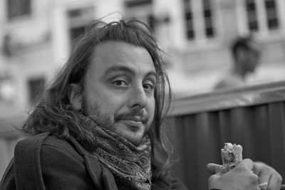 Portrait of smiling man eating food in city