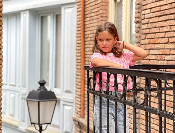 Portrait of young woman standing against wall