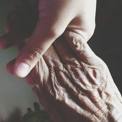 Cropped image of woman holding grandmother hand at home