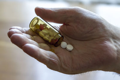 Close-up of hand holding pill bottle