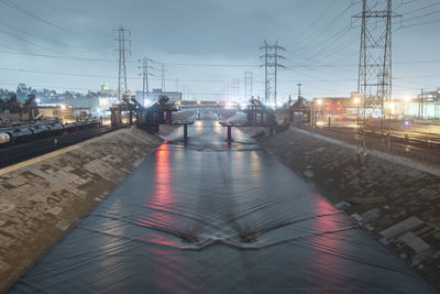 Cars on illuminated bridge against sky in city