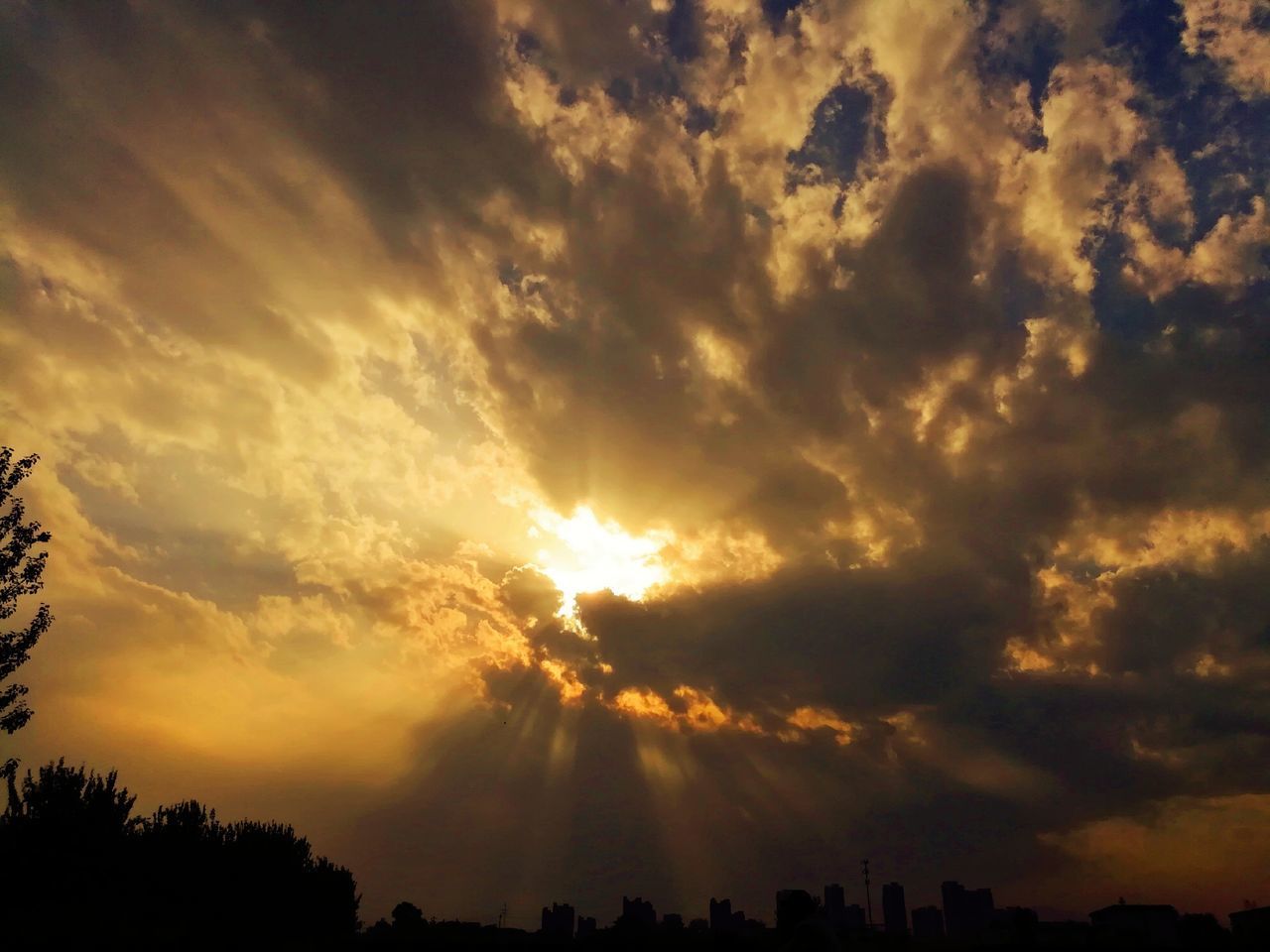 LOW ANGLE VIEW OF SUNLIGHT STREAMING THROUGH CLOUDS